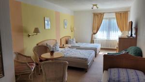 a hotel room with two beds and a table at Waldpension Am Köpfchen in Kurort Steinbach-Hallenberg