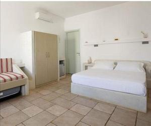 a white bedroom with a bed and a couch at Guardiero in Kithnos