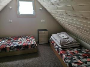 a attic bedroom with a bed and a window at Drewniane domki w Wilkasach in Wilkasy