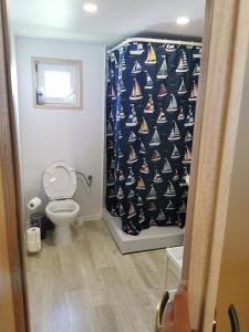a bathroom with a toilet and a shower curtain with sailboats at Drewniane domki w Wilkasach in Wilkasy