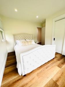 ein weißes Bett in einem Schlafzimmer mit Holzboden in der Unterkunft The Cottage at Glenwood Retreats 