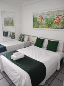 um quarto com 2 camas com almofadas verdes e brancas em Hotel Porto Verde -JG em Porto Seguro