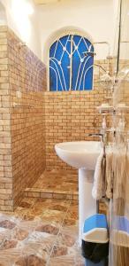 La salle de bains est pourvue d'un lavabo et d'une fenêtre bleue. dans l'établissement HabuHeritageHomeStayInLuxor, à Al Aqālitah