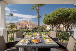 a table with food on a balcony with palm trees at Casa Ch'i - Vale de Lobo in Vale do Lobo