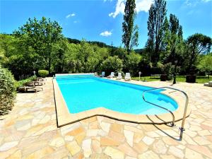 una piscina en un patio con sillas y árboles en Gîte et chambres d'hôtes LE MERCOIRE, en Aubenas