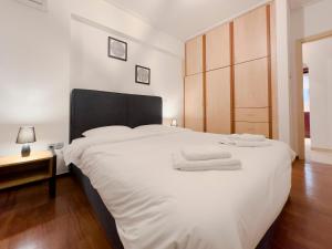 una camera da letto con un grande letto bianco con asciugamani di Kairi Cozy 92sqm apt in Nea Smirni ad Atene
