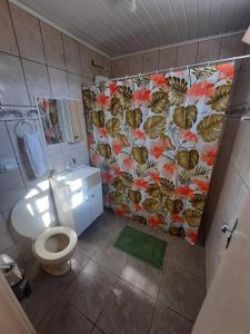 uma casa de banho com um WC e uma cortina de chuveiro de flores em Suíte Azul com SmartTv, Cama Queen e Banheiro Privativo em Itajaí