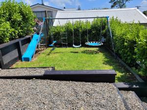 a playground with two swings in a yard at Alta House in Auckland