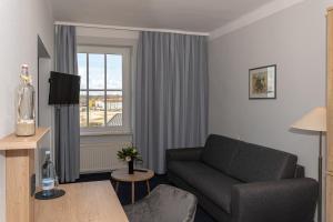 Kurhotel Sassnitz في ساسنيتز: غرفة معيشة مع أريكة ونافذة