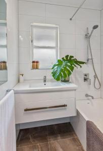 a white bathroom with a sink and a window at Alta House in Auckland