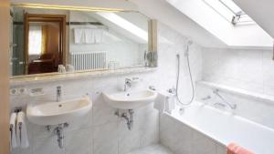 ein Badezimmer mit zwei Waschbecken, einer Badewanne und einem Spiegel in der Unterkunft Landhaus Seeblick in Füssen