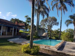 - une piscine en face d'une maison avec des palmiers dans l'établissement Sítio Santa Filomena - São Roque, à São Paulo