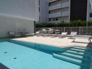 uma piscina com espreguiçadeiras e um edifício em Jesolo Appartamenti F2 - Coral Red em Lido di Jesolo
