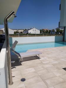 - une piscine avec chaise longue à côté de la piscine dans l'établissement Jesolo Appartamenti F2 - Coral Red, à Lido di Jesolo