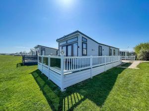 ein winziges Haus auf dem Rasen auf einem Feld in der Unterkunft Beautiful Lodge With Full Sea Views At Broadland Sands In Suffolk Ref 20235bs in Hopton on Sea