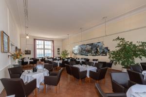 a dining room with white tables and black chairs at Kurhotel Sassnitz in Sassnitz