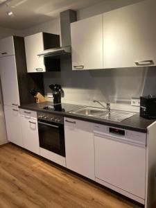 a kitchen with white cabinets and a stove and a sink at Appartement Stefanie in Hollersbach im Pinzgau
