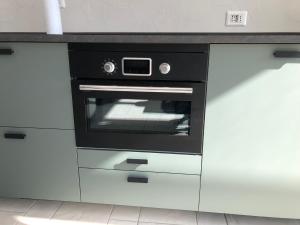 un horno negro en una cocina con armarios blancos en Attico 24, Residence Gardalido, en Padenghe sul Garda