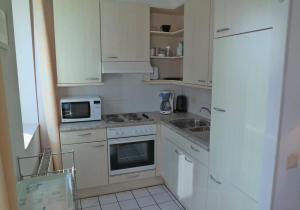 a kitchen with white cabinets and a sink and a microwave at Terminated in Cadzand