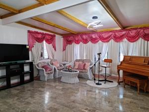 un salon avec une télévision et un piano dans l'établissement 150 Lucap Road, à Alaminos