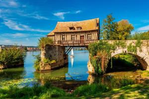 a bridge over a river with a building on it at Les Bouches Manon in Pressagny l'Orgueilleux