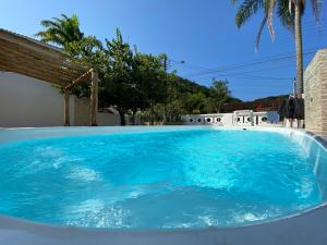 una gran piscina con agua azul en un patio en Casa em condomínio a 500m da praia de Pernambuco ideal para família, en Guarujá