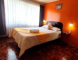 a bedroom with a bed with orange walls and a window at Hotel Express in La Paz