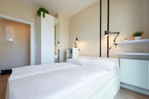 um quarto com uma cama branca com lençóis brancos em VacationClub - Let’s Sea Baltic Park C83 em Gąski
