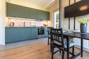 a kitchen with blue cabinets and a table and chairs at VacationClub - Let’s Sea Baltic Park C83 in Gąski