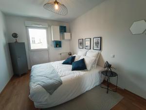 ein Schlafzimmer mit einem großen weißen Bett mit blauen Kissen in der Unterkunft T3 Lumineux - Berges de la Garonne - Parking in Toulouse