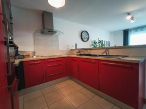 een keuken met rode kasten en een wastafel bij T3 Lumineux - Berges de la Garonne - Parking in Toulouse