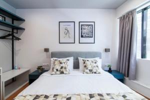 una camera da letto con un grande letto bianco con cuscini di Olvia Suites ad Atene