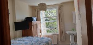 1 dormitorio con ventana, 1 cama y lavamanos en Barmy Badger Backpackers, en Londres