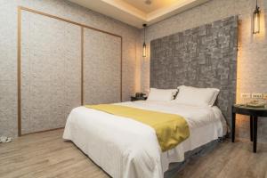 1 dormitorio con 1 cama grande y pared de piedra en 沐-湯宿溫泉行旅, en Jiaoxi