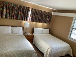 two beds in a small room with two windows at Carr's Northside Hotel and Cottages in Gatlinburg