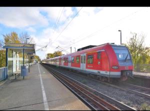 Um comboio vermelho está a chegar a uma estação de comboios. em SECOND HOME bitte beachten Sie den Check in und Check out em Neuss
