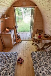 a room with a wooden floor and a room with a guitar at Campingpod back to basic in Tønder