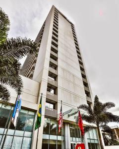 un edificio alto con banderas delante en True América apart-hotel, en Campos dos Goytacazes