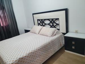 una camera da letto con un letto con un piumone bianco e nero di Appart calme, neuf à 5mn de la plage SAADIA a Saïdia