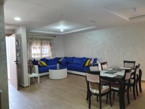 uma sala de estar com um sofá azul e uma mesa em Appart calme, neuf à 5mn de la plage SAADIA em Saidia 