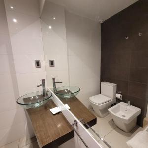 a bathroom with two sinks and a toilet at Guemes Apartment in San Juan