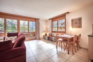 ein Wohnzimmer mit einem Tisch, Stühlen und Fenstern in der Unterkunft Apartment Mountain View, Luxury, Spacious with best Views in Lauterbrunnen