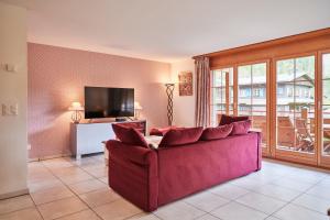 a living room with a red couch and a television at Apartment Mountain View, Luxury, Spacious with best Views in Lauterbrunnen