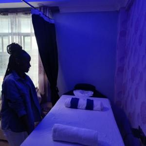 Eine Frau steht in einem blauen Zimmer mit einem Bett in der Unterkunft Kentania Hotel & Spa, Nakuru - Kenya in Nakuru
