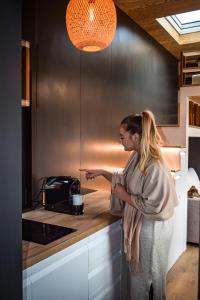 Eine Frau steht in einer Küche neben einem Toaster. in der Unterkunft Coniferis in Tomnatic