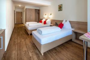 two beds in a room with wooden floors at Ferienhotel Fuchs in Söll