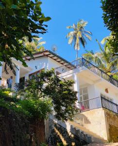 a white house with a palm tree in the background at Pearl's Homestay Matale in Matale