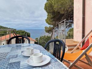 una mesa con tazas y platillos en el balcón en Villa Mirella Trilocale, en Capoliveri