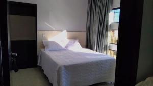 a bedroom with a white bed and a window at HOTEL VIZON II in Vilhena