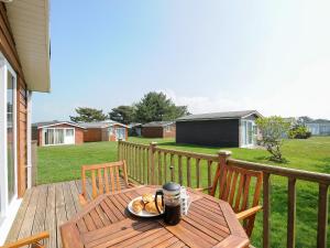 een houten tafel met een bord eten op een veranda bij Little Trebah in Saint Merryn